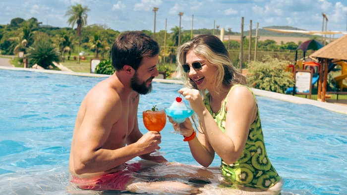 casal com drinks na piscina