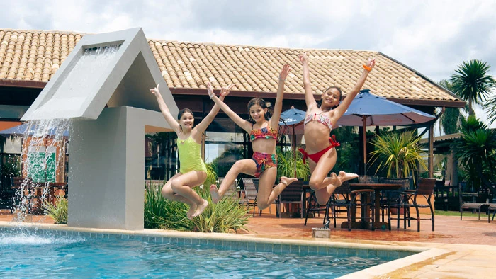 três meninas saltando na piscina